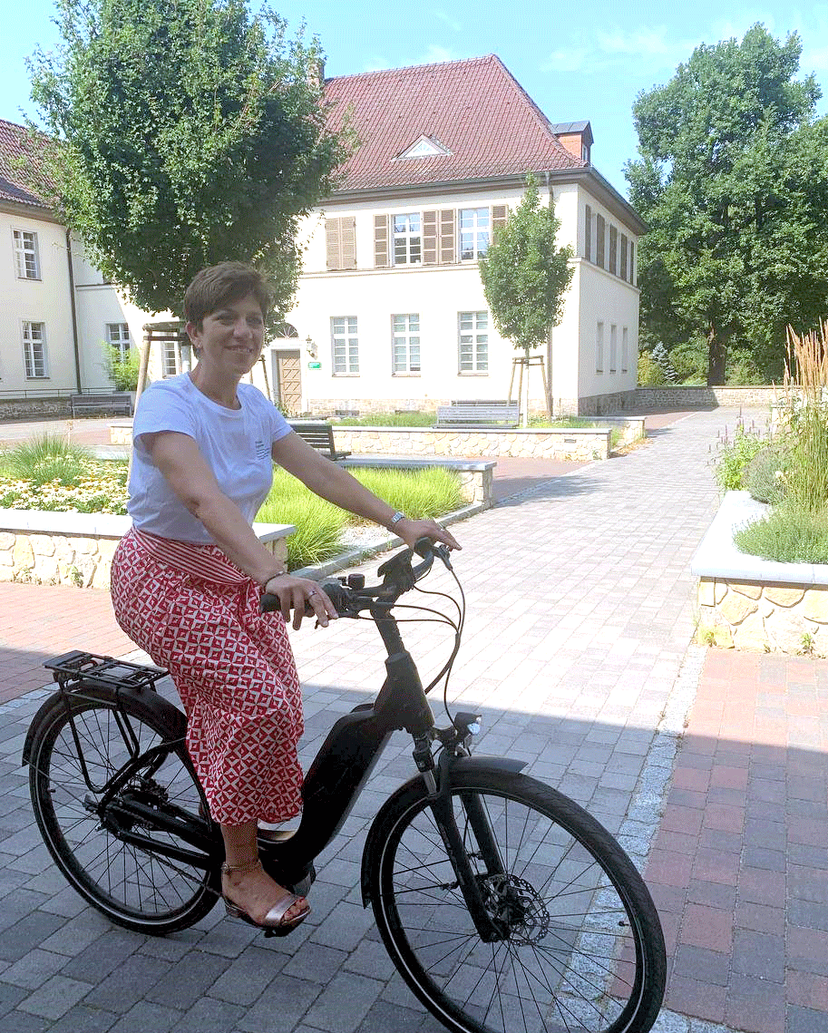 Anita auf einem E-Bike vor dem Büro in Müncheberg