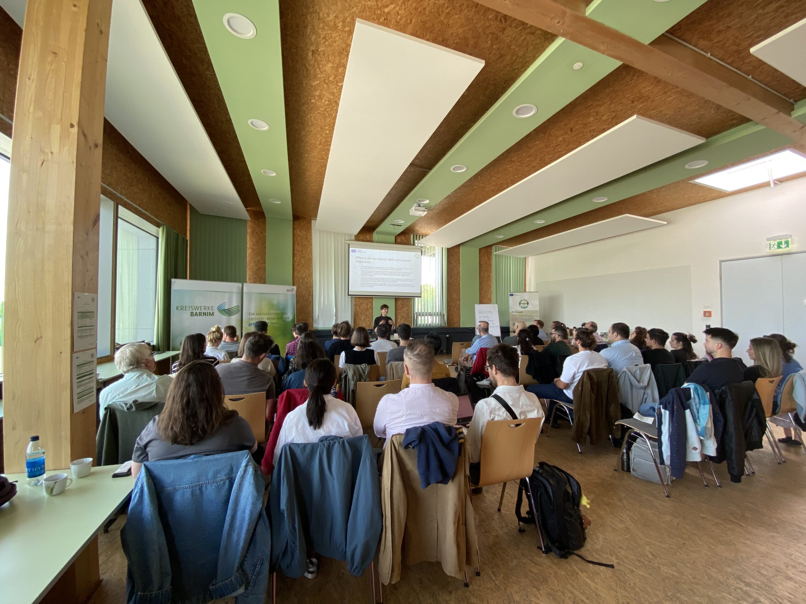 Menschen sitzen in einem großen Saal und hören einem Vortrag zu.