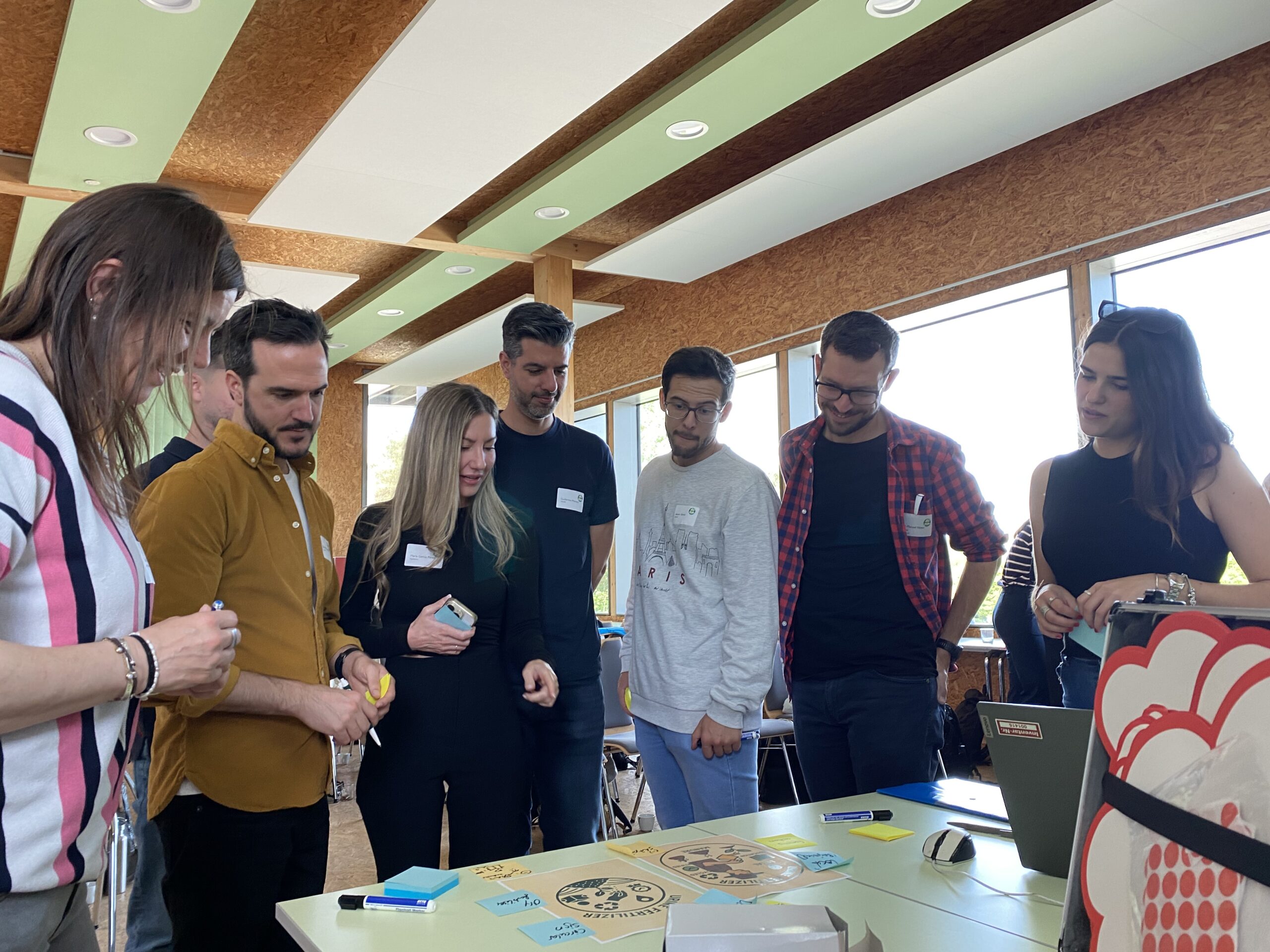 Eine Gruppe schaut bei einem Workshop auf einen Tisch mit Notizen.